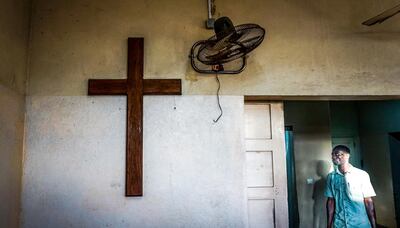 A morgue worker stands at the entrance to the freezer area next to a cross where prayers are made before families take their relatives away in Beira, Mozambique. March 22, 2019. Jack Moore / The National