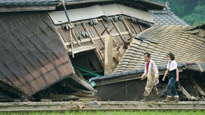 A couple walks in front of houses damaged by flood in Kuma village, Kumamoto prefecture, southwestern Japan. AP