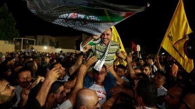 A released Palestinian prisoner Esmat Mansour, waves a flag as he is cheered at the Palestinian Authority headquarters in the West Bank city of Ramallah. AP Photo / Majdi Mohammed