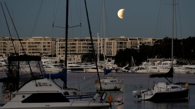 The moon begins to set over Sydney harbour during the eclipse in Australia. AP Photo/Rick Rycroft