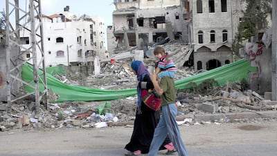 Palestinians in northern Gaza pass by a home damaged by an Israeli air strike. Photo: Heidi Levine for The National.