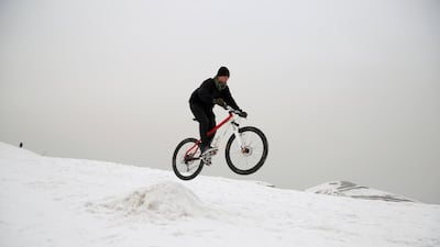 An Afghan boy rides a bicycle in the snow on the outskirts of Kabul, Afghanistan. AP