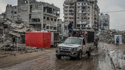Palestinians drive down a muddy road after the first winter rainfall in a camp for displaced people, in Gaza city. AFP