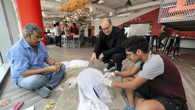 Hani Asfour (in black), associate dean at DIDI, looks on as Jatin Aidasani creates his version of life on Mars, rendered using mud, glue, sand, paper and synthetic cloth. Chris Whiteoak / The National