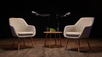 Two stylish chairs face each other in a sleek podcast studio, ready for an enriching interview session. Microphones dangle from above, creating an inviting atmosphere for storytelling. Getty Images