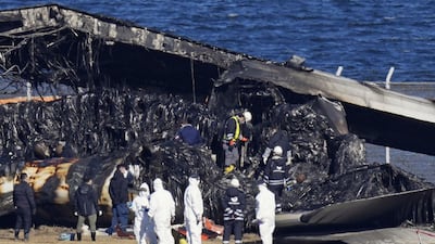 Officials inspect the wreckage of the Japan Airlines passenger plane at Haneda Airport in Japan. AP
