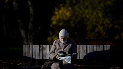 A reader, wearing a face mask amid the ongoing pandemic, on a bench at a park in Moscow on October 18. AFP