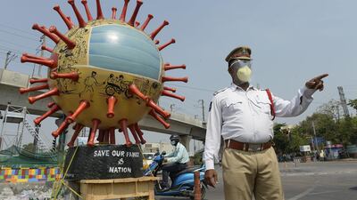 An Indian traffic officer stands beside a coronavirus-themed globe at a traffic junction as he checks commuters travelling during a government-imposed nationwide lockdown in Hyderabad. AFP