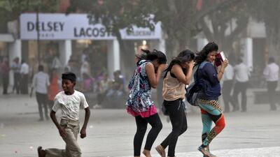 A boy runs next to women trying to shield themselves from a dust storm at a shopping arcade in Chandigarh. Ajay Verma / Reuters