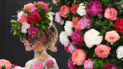 A model poses for photographers next to a floral display during the press day for the RHS Chelsea Flower Show in London, Britain. EPA