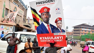 A supporter of Ugandan opposition presidential candidate Robert Kyagulanyi Ssentamu, also known as Bobi Wine, carry a campaign poster ahead of the presidential and parliamentary elections, in Kampala, January 12, 2021. Reuters