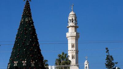 A Christmas tree stands near the minaret of a mosque and the bell tower of a church in Bethlehem. AFP