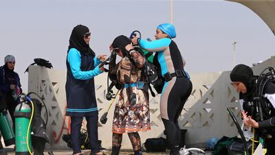Bothaina Al Yousef and Dana Al Qatari help their fellow diver Zynab Al Magaslah put on her diving equipment. Reuters