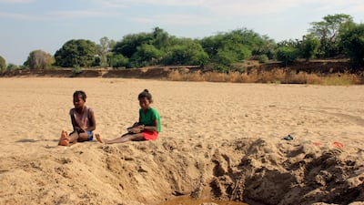 Children by a dug out water hole in a dry river bed in the village of Fenoaivo, in Madagascar. AP