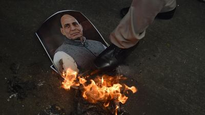 A policemen tries to extinguish a burning poster bearing the image of Indian Home Minister Rajnath Singh during a demonstration by activists from the right-wing Hindu Sena organisation in New Delhi. Sajjad Hussain / AFP