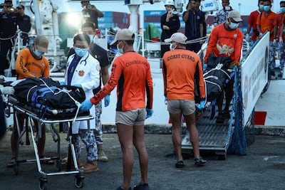 Philippine coastguard personnel carry body bags after a ferry capsized off the southern Philippines, as search efforts continue. Reuters