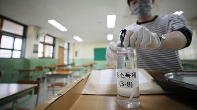 A teacher at a high school in in Seoul, South Korea, prepares hand sanitiser for pupils as a precaution against Covid-19 before classes restart. AP