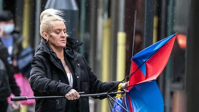 A woman with a broken umbrella walks windy conditions in Leeds. PA