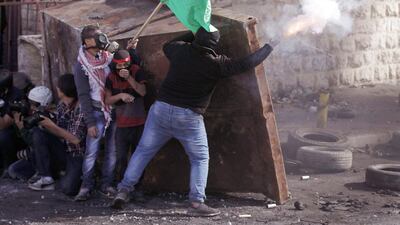 Palestinians and photographers take cover behind a container during clashes with Israeli security forces in the Palestinian refugee camp of Shuafat in East Jerusalem on November 7, 2014. Ahmad Gharabli / AFP