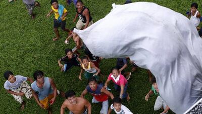 Survivors of Super Typhoon Haiyan wait for a sack containing food supplies to drop from a Philippine Air Force helicopter in Tolosa, Leyte in central Philippines November 21, 2013. Typhoon Haiyan, which hit Philippines on November 8, killed more than 4,000 people and left another 4 million homeless. REUTERS/Erik De Castro (PHILIPPINES - Tags: DISASTER ENVIRONMENT FOOD TRANSPORT)