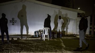 Shadows of men, members of the Phoenix Community Policing Forum, a grassroots mobilisation group involving local residents, are cast on the outside wall of a house while he and other members are on a lookout in Durban, on July 20, 2021. - Phoenix is flashpoint town between black South Africans and counterparts of Indian origin where at least 20 people died in the recent wave of violence. Like communities across South Africa, residents of the predominantly ethnic Indian town set up their own protection squads in response to pillaging and arson that broke out days after the jailing of ex-president Jacob Zuma on July 8th -- overwhelming security forces.