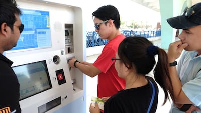 Commuter Arlean Alcampado tries out the new Hafilat fare card system for buses in Abu Dhabi at the city's main bus terminal on Friday. Delores Johnson / The National