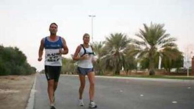 Mark Palfreeman and Karen Betton jog on the street near the public beach past the Emirates Palace.