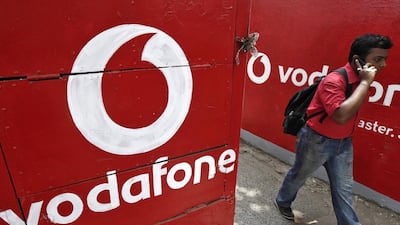 A man speaks on his mobile phone as he walks past logos of Vodafone painted on a roadside wall in Kolkata. Rupak De Chowdhuri / Reuters