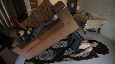 Palestinian fitness trainer and bodybuilding Ahmed Sawi uses alternative tools as a weight as he trains at his home in Gaza City. AFP