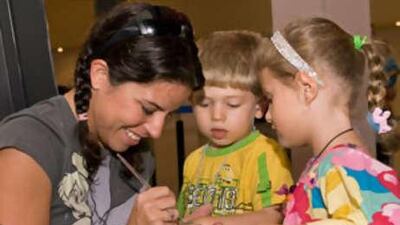 The make-up artist Lili Inker entertains Elmalki, left, and Alexia Steer with some hand painting during the recent Cinemama event at Mercato Mall in Dubai.