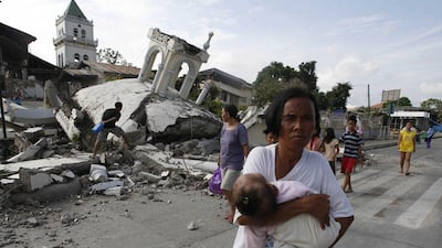 A woman carries her baby past a destroyed church in Tubigon, Bohol, a day after an earthquake hit central Philippines. Erik de Castro / Reuters
