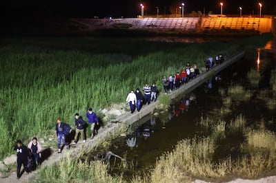 Immigrants walk from Mexico into the US on their way to await processing by the US Border Patrol on May 23, 2022 in Yuma, Arizona. Getty Images / AFP
