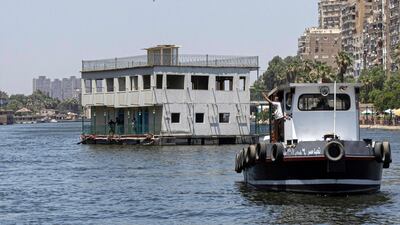 One of the houseboats usually moored across one of the banks of the Nile river between the Zamalek district of Egypt's capital Cairo (R) and the Agouza district of its twin city of Giza (L) is towed away by authorities on June 27, 2022, as part of a wider decree to clear all of the river's banks in the area. - Urban reprieve for some, life savings for others, around thirty Nile of the houseboats, known as "awamat" (floating), are slated for demolition in Cairo, with residents claiming the state is sacrificing heritage for profit. A campaign to save the houseboats has been launched online, with a petition garnering more than 4,000 signatures. The vessels hold cultural weight even beyond the Nile, cemented in Arab cinema as the sight where Abdel Halim Hafez crooned in 1955's 'Ayam w Layali' (Days and Nights) and the setting for the titular chitchat in 1971's 'Tharthara fawq al-Neel' (Chitchat on the Nile), based on the novel by Nobel Prize-winning Naguib Mahfouz. (Photo by Khaled DESOUKI / AFP)