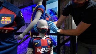 An employee places a mask with the logo of FC Barcelona on a mannequin at the FC Barcelona store. AFP