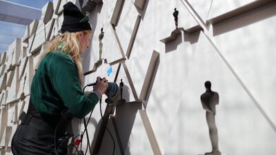 A worker sands an Oscars backdrop. Reuters