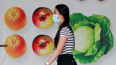 A woman wearing a protective mask walks outside a mall in Manila, Philippines. AP