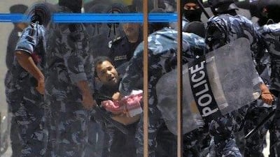 Kuwait riot policemen arrest a man during a demonstration in Kuwait City on Monday. Several thousand protesters gathered in the city to demonstrate against the government’s amendment of the electoral law.