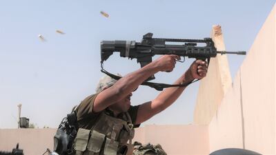 An Iraqi soldier sprays fire at an ISIL position across the road in west Mosul. Florian Neuhof for The National