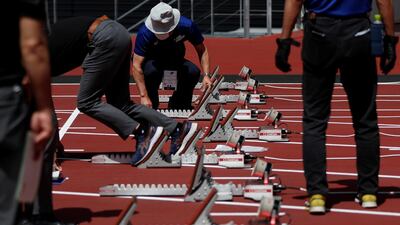 Officials check on starting blocks before the start of the morning session of the athletics test event. Reuters