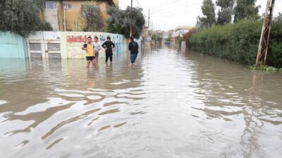 Iraqis stand amid a flooded street in Mosul. EPA
