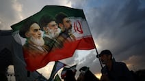 A man holds a flag depicting the late leader of the Islamic Revolution, Ayatollah Ruhollah Khomeini, late supreme leader Ayatollah Ali Khamenei and new supreme leader Mojtaba Khamenei, during a rally in Tehran. Reuters