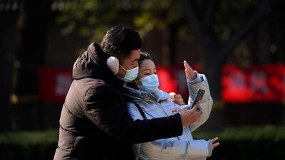 A couple wearing face masks to help curb the spread of the coronavirus take a selfie near the drum tower, a tourist spot in Beijing. AP Photo