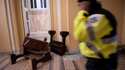 A US Capitol police officer passes in front broken furniture and shattered glass at the Capitol building. Bloomberg