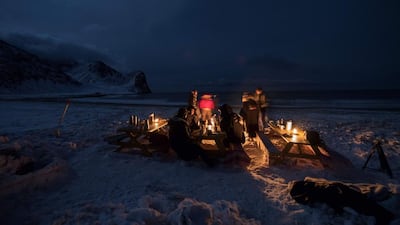 Surfers rest in front of a camp fire after an evening of surfing.