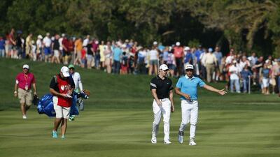 Rickie Fowler, right, of the United States and Rory McIlroy of Northern Ireland walk in the field during the second round of the Abu Dhabi HSBC Championship on January 22, 2016. / AFP / KARIM SAHIB