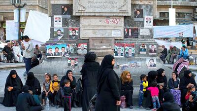 Syrians sit in front of campaign posters for parliamentary candidates in Damascus' Marjeh square on April 11, 2016. The government’s insistence on holding its own parliamentary elections could be perceived as a sign of ill will by the opposition and cause friction in Geneva. Hassan Ammar/AP Photo