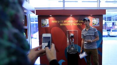 Visitors take photographs with the Fifa U-17 World Cup winner’s trophy displayed during the launch of the trophy tour at Abu Dhabi's Marina Mall last month. Ravindranath K / The National