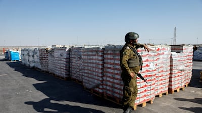 An Israeli soldier stands next to parcels of humanitarian aid waiting to be transferred into Gaza at the Gaza part of the Kerem Shalom crossing. Reuters