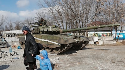 Mariupol residents walk past a tank belonging to pro-Russian forces in the besieged southern port city. Reuters