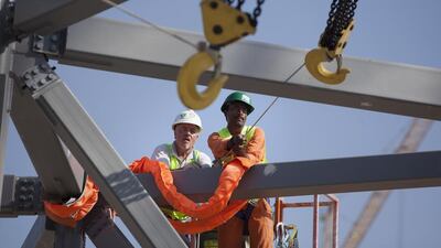 An engineer and a flagman pull in a crane hook as they work on the installation of the super-sized element. Silvia Razgova / The National